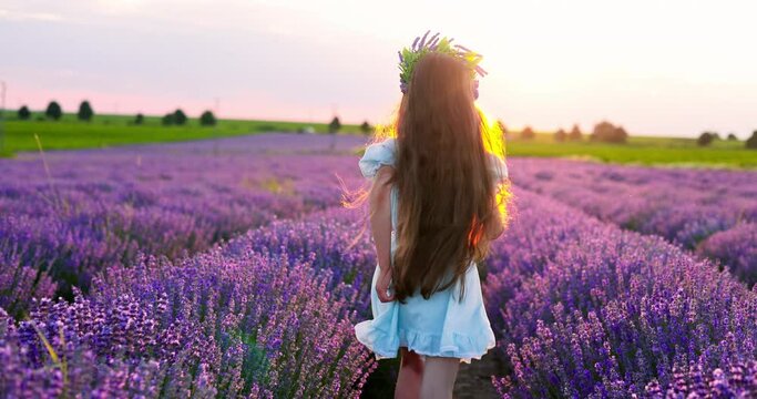 Joyful girl, beautiful woman running in endless blooming lavender fields during scenic sunset