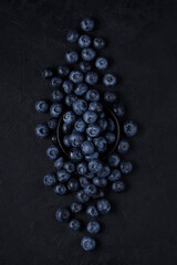 ripe blueberries are beautifully scattered on the table with a black plate. top view. artistic moody photo
