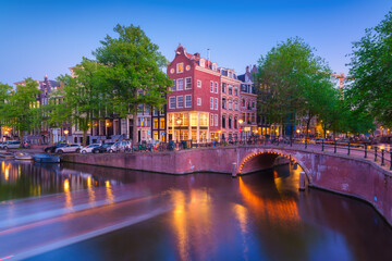 Fototapeta premium Amsterdam, Netherlands. View of houses and bridges during sunset. The famous Dutch canals and bridges. A cityscape in the evening. Travel photography.