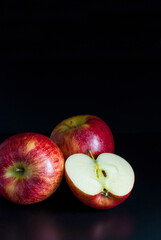 Red apples, whole, and halves on a black background.