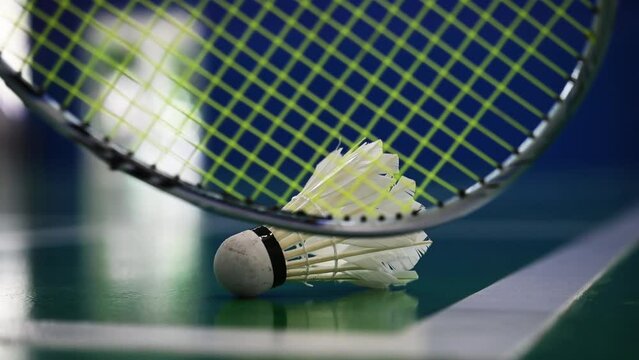 badminton racket scooping shuttlecock from court ground