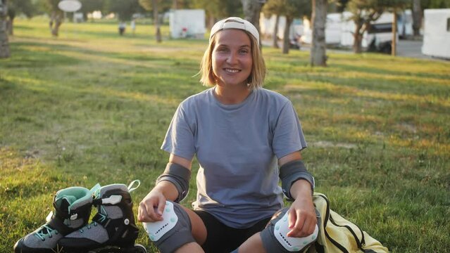 Portrait of sporty young woman sitting on lawn look at camera smiling in summertime. Healthy lifestyle and sports concept.