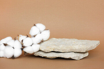 Stone Podium for promotion on beige Background. Natural pedestal. Rock. Beauty product mockup. Scene to show products. Showcase, display case. Front View, soft shadow. Cotton flowers, wooden branch