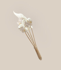 Whipped cream at flying wooden whisker at pale beige background. Levitation food concept with baking utensils. Front view.