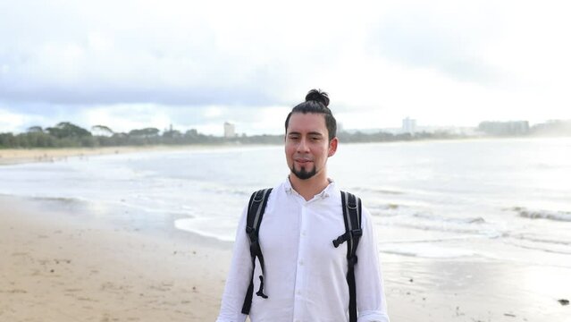 海の前で微笑むバックパックを背負ったヒスパニック男性