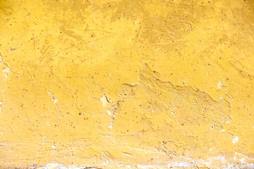 Old dirty concrete wall with cracked and peeling texture on yellow background