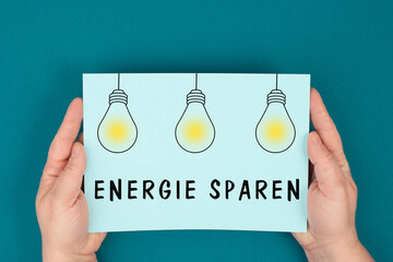 Save energy is standing in german language on the paper, light bulbs, increase of electricity and...
