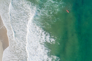 Aerial view of sandy beach and ocean with waves surfer waiting for the good wave