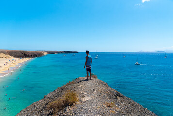 Un turista mirando la playa Mujeres desde un un pico de montaña alto, con camiseta azul y de...