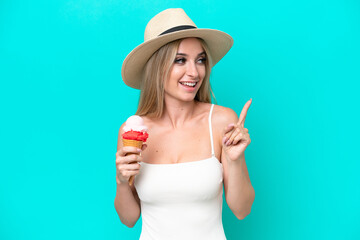 Blonde woman in swimsuit holding an ice cream isolated on blue background intending to realizes the solution while lifting a finger up
