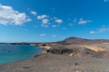 vista de un costado del a playa de la cera en Lanzarote en las islas canarias. día soleado de verano en canarias. con el mar turquesa y un volcán de fondo.