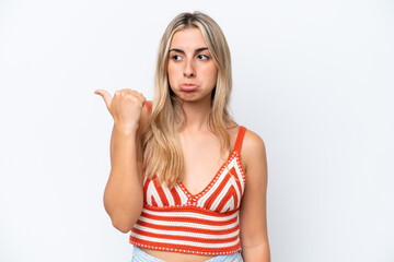 Young caucasian woman isolated on white background unhappy and pointing to the side