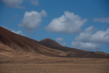 Vista panorámica del Parque Nacional de Timanfaya, impresionante paisaje volcánico y desértico con  montañas en sombra durante un día soleado con el cielo azul y nubes en Lanzarote Islas Canarias.