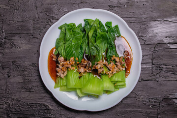 Baby Bok choy or chinese cabbage in oyster sauce with fried garlic. on black background.