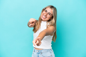 Young caucasian woman isolated on blue background pointing front with happy expression