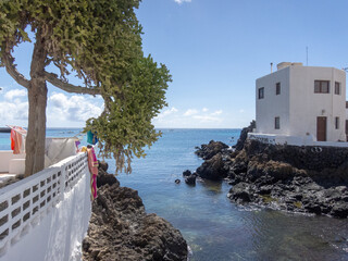 Arquitectura blanca tradicional de Lanzarote junto a una entrada al mar cristalino, vegetación y...