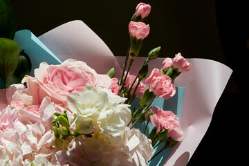 A bright bouquet of flowers in festive wrapping paper on a dark background.