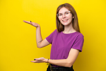 Young English woman isolated on yellow background holding copyspace to insert an ad