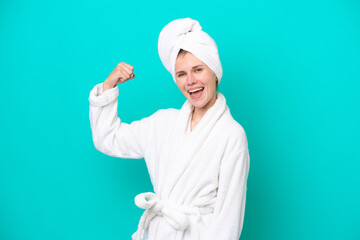 Young woman in a bathrobe isolated on blue background doing strong gesture