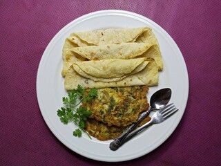 Delicious hand made fried paratha with semolina and fork on  wooden table. Top view of Asian food dish.