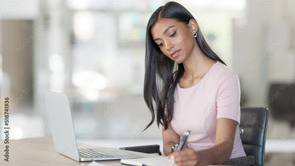 Sticker young business woman using a laptop to work online and taking notes in her diary in an office at wor