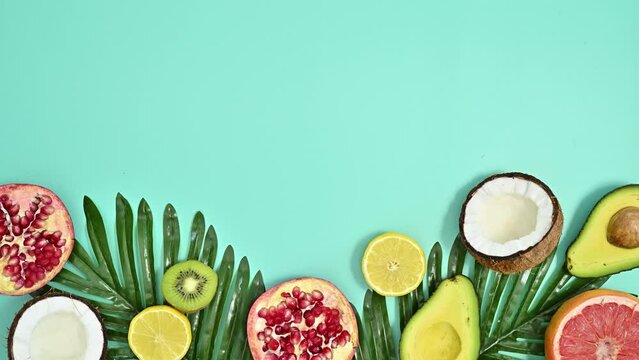 Summer tropical arrangement with natural palm leaves and exotic fruits on cyan background. Stop motion flat lay. Copy space