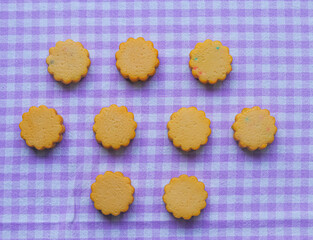 Round butter cookies arranged on a purple table cloth