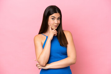 Young Brazilian woman isolated on pink background and thinking