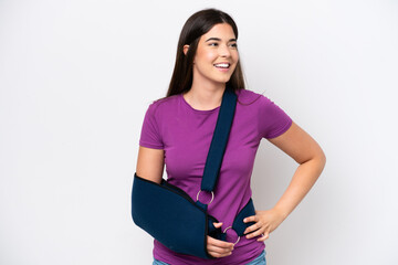 Young Brazilian woman with broken arm and wearing a sling isolated on white background posing with...