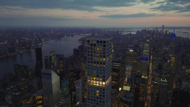 Evening aerial panoramic footage of midtown with tall skyscrapers surrounded by water surface. Colourful twilight sky. Manhattan, New York City, USA