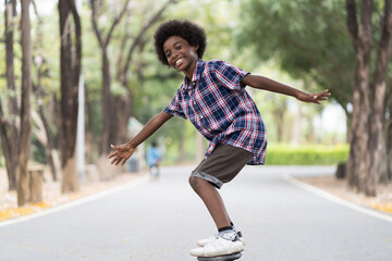 Boy playing on skateboard. African American boy riding skateboard in the road. Kid practicing skateboard. © amorn