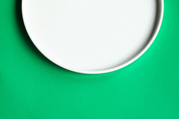 White plate on a green background, top view.