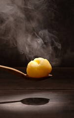 one boiled potato on wooden spoon