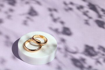 Gold rings on a purple background with shadows.