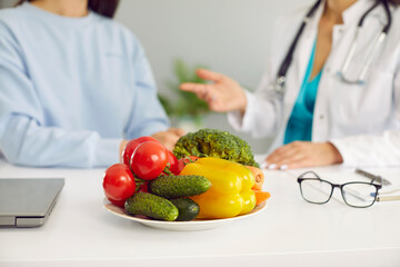 Fresh healthy vegetables in plate cucumbers, tomatoes and bell peppers containing vitamins on table of nutritionist doctor symbolize benefits of proper nutrition and vegetarianism. Selective focus