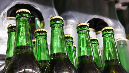 Close-up of many beautiful green glass bottles of beer on a store shelf