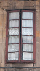 Ventana rústica con cortina de encaje en fachada de piedra de palacio