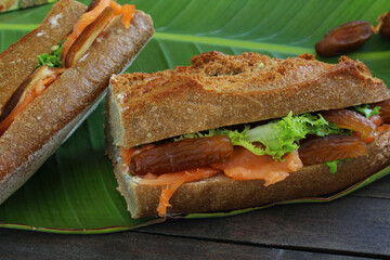 Close up breakfast sandwich with smoked salmon and date fruit on banana leaf