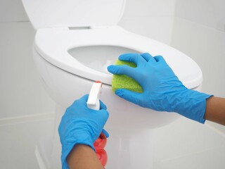 Woman hands on blue gloves cleaning a WC. closeup photo, blurred.