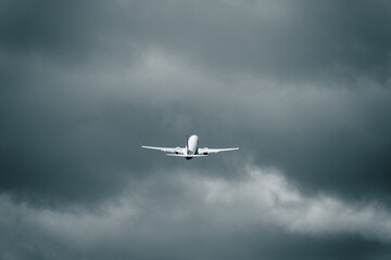 Passenger aircraft flying in the cloudy sky after take off. Heavy cumulonimbus clouds in the...