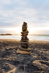 Fototapeta na wymiar Stack of Stones Balance on a Beach Against a Cloudy Sky at Sunset Time.Zen Concept.Vertical Image