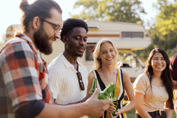 A happy group of middle-aged friends are traveling the world in an RV. The young people meet at a campsite.