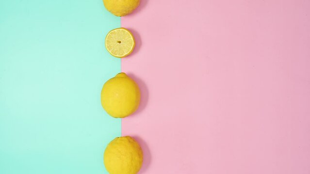 Creative moving lemons on pastel pink and cyan background. Summer tropic stop motion. Copy space flat lay