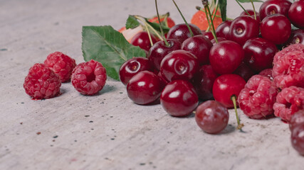 Close - up view to appetizing, fresh, juicy, ripe cherry and raspberry assortment on light gray background