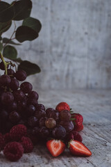 Appetizing, fresh, juicy, ripe grapes,  strawberry and raspberry assortment on light gray background. 