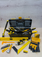 Yellow construction instruments and a tool box on a wooden background.