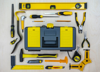 Construction instruments and a tool box on a plywood background. All tools and a box with yellow...