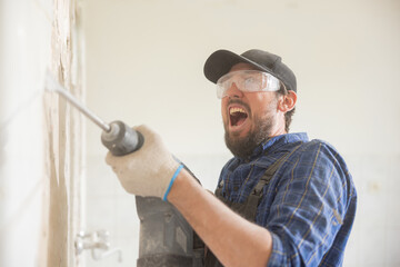 A man's shout of anger terrifies while hammering tiles in a house under renovation. Guy wearing...