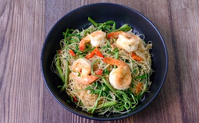 Top view table stir fried rice noodle with shrimp and water minosa vegetable or Mee Phat Krachet Koong in Thai.