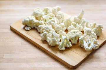 Cauliflower florets on a wooden cutting board, prepared ingredient for cooking a vegetable dish, copy space, selected focus